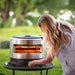 Caucasian woman with blonde hair holding the gas knob of the solo stove pi prime pizza oven