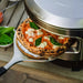 baked pizza being carried out of a solo stove pi prime pizza oven